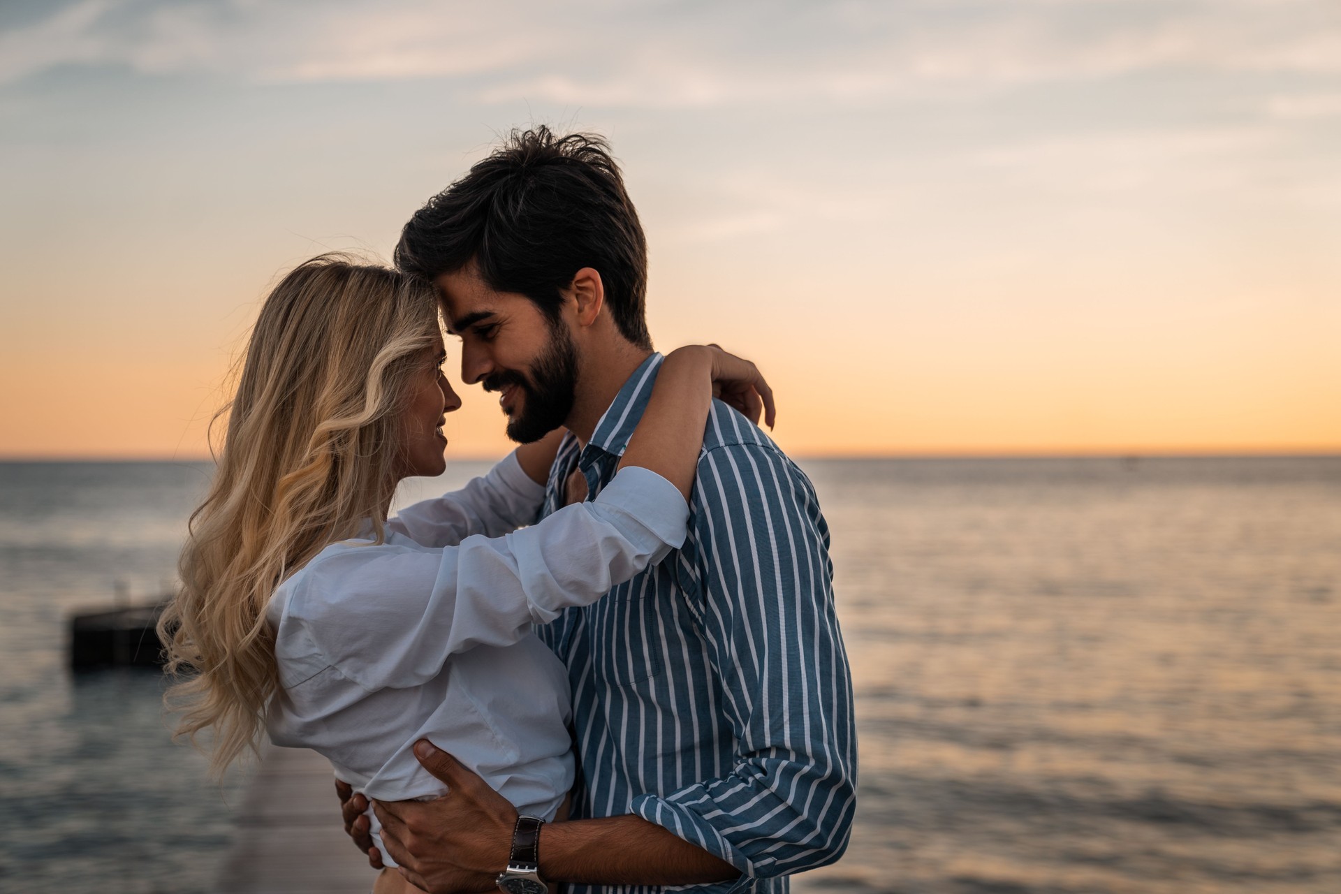 Beautiful couple in love standing face to face at sea dock